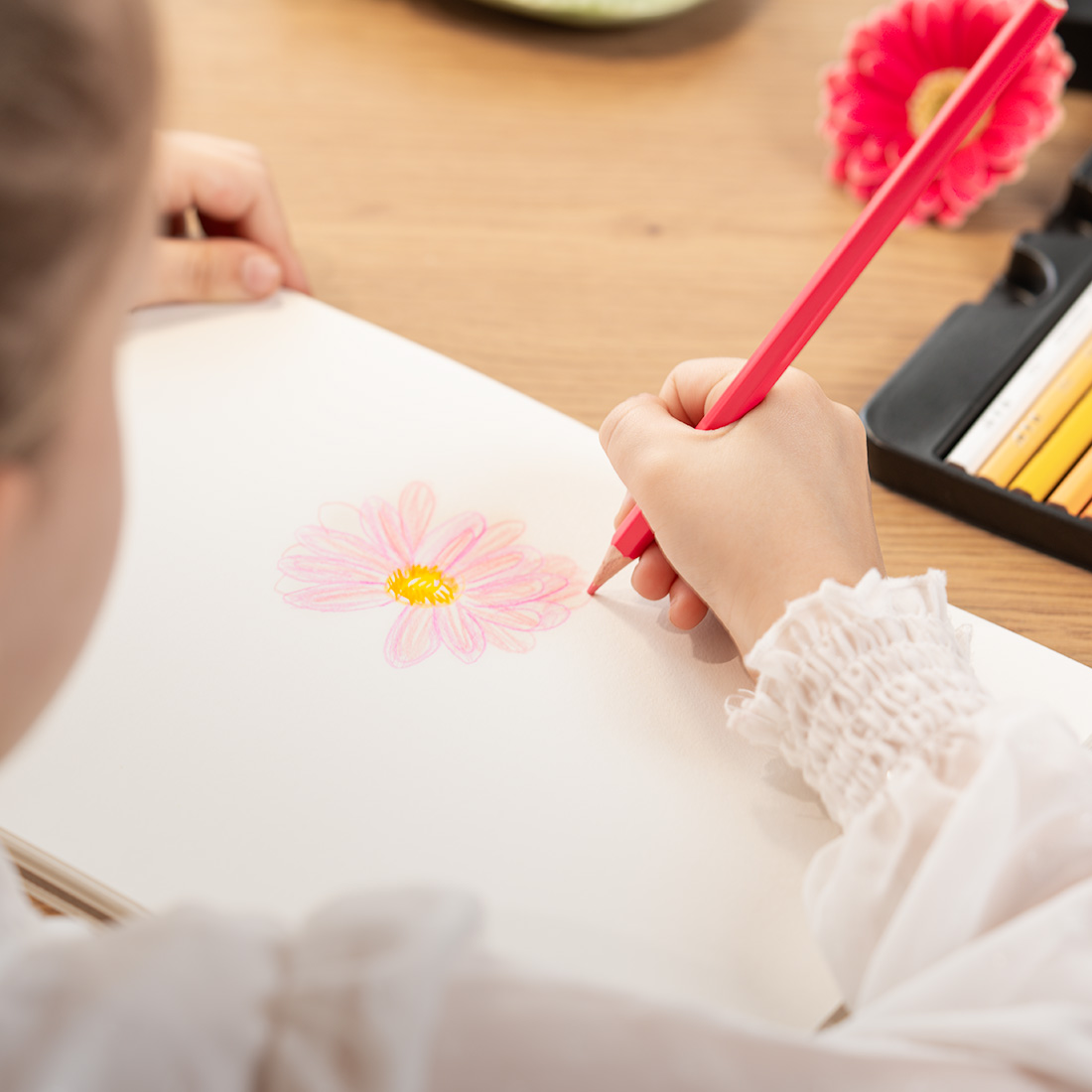 Artist concentrat desenand cu creioane acuarela, mana tinand creionul ergonomic, detalii fine pe hartie artistica, evidentiind usurinta in utilizare